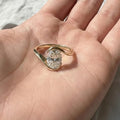 Oval cut diamond bypass engagement ring with asymmetrical open wrap gold band and modern solitaire setting.