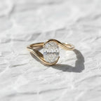 Oval cut diamond bypass engagement ring with asymmetrical open wrap gold band and modern solitaire setting.